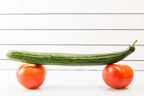 Imagen conceptual del skateboarding y la alimentación saludable. Dos tomates con pepino —  Fotos de Stock