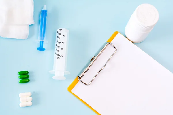 Medische conceptuele afbeelding met pillen, injectie, gaas, fles, lege Klembord blad. — Stockfoto