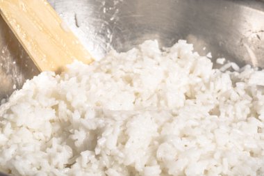 Metal bir kase ve tahta kaşık karıştırıcı beyaz pirinç pişmiş