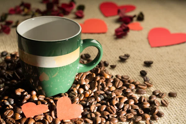 Tasse de café avec des haricots et des coeurs dispersés papier — Photo