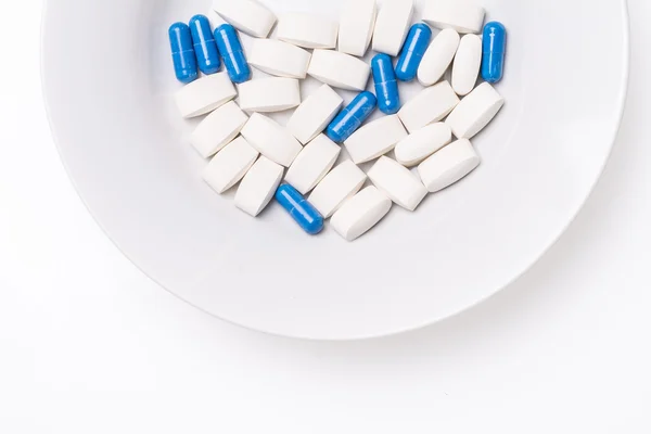 Тарілка з біло-блакитними медичними таблетками для лікування захворювань — стокове фото