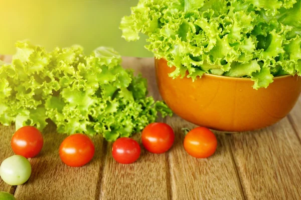 green lettuce salad and tomatoes on wooden with green nature background