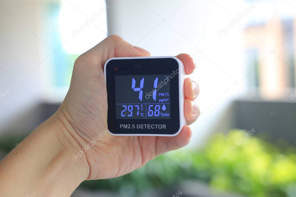 Checking air quality with hand held PM2.5 sensor device. PM2.5 particles dust at harmful unhealthy beyond acceptable standard.