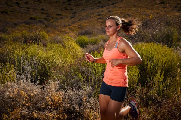 Rubia corredor sendero femenino corriendo a través de un paisaje de montaña — Foto de Stock