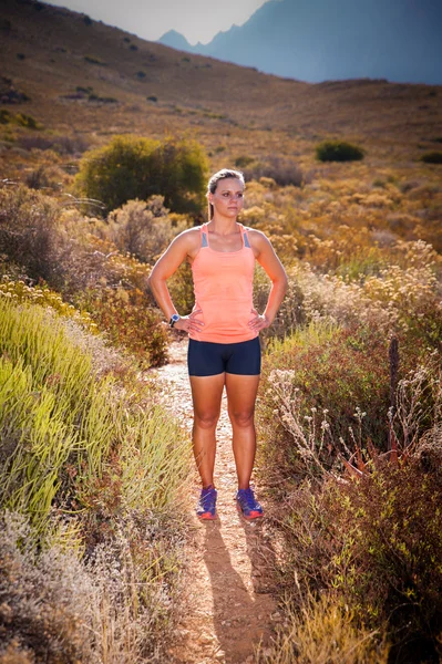 Blonďatá samice stezka běžec běží přes horské krajiny — Stock fotografie