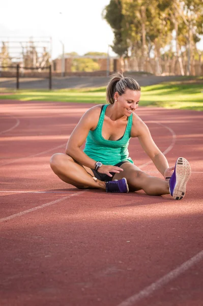 Female athlete stretching on a running track — Stock Photo, Image