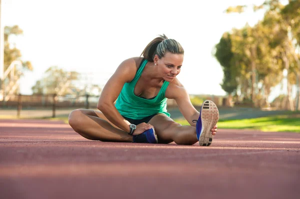 Female athlete stretching on a running track — Stock Photo, Image