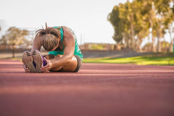 Female athlete stretching on a running track — Stock Photo, Image