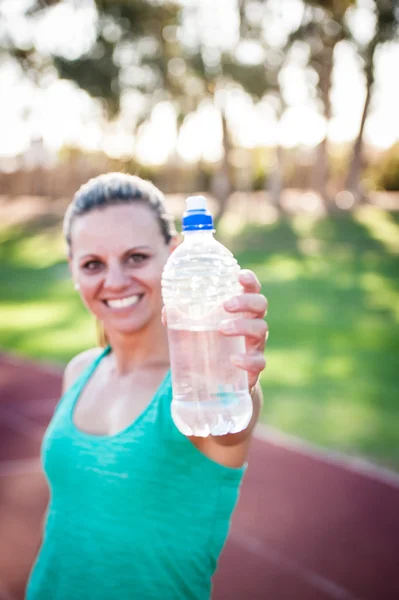 Female athlete holding a water bottle — Stock Photo, Image