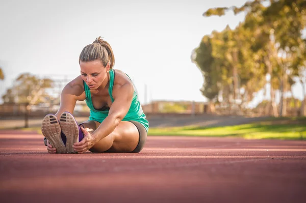 Athlète féminine s'étirant sur une piste de course — Photo