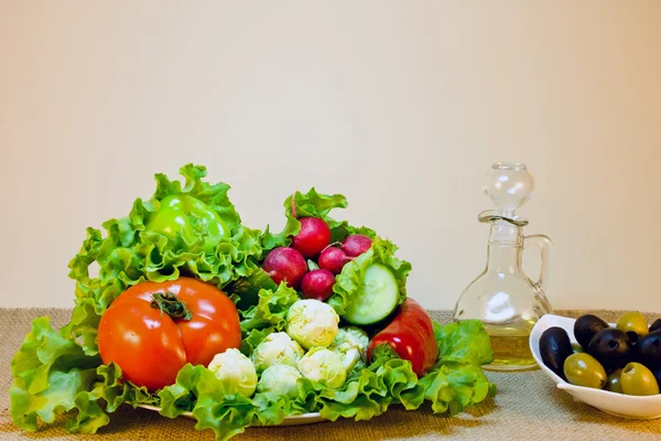 Stillleben von frischem Gemüse auf einem Teller und Oliven in einer Sauce — Stockfoto