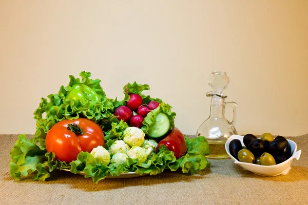 Stillleben von frischem Gemüse auf einem Teller und Oliven in einer Sauce — Stockfoto