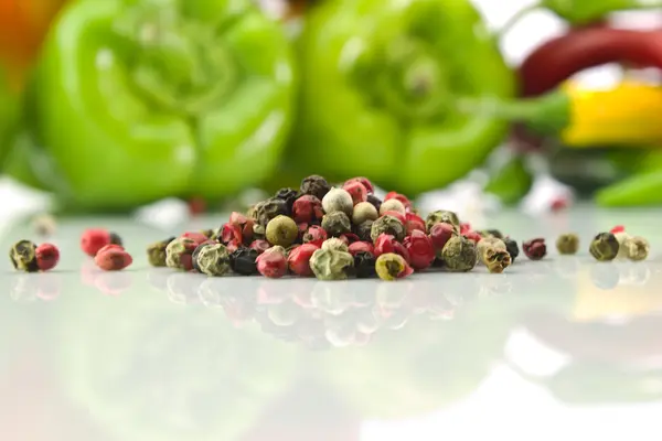 Pepper grains on a background of green pepper — Stock Photo, Image