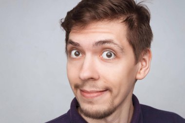 Yakışıklı, gülümseyen genç bir adamın yakın plan portresi. Hafif arka plan stüdyo çekimlerinde izole edilmiş neşeli adamlar. Küçük sakallı ve modern saç kesimli erkekler.