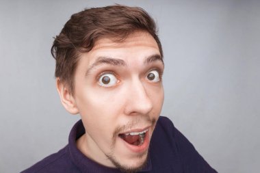 Heyecanlı beyaz tenli bir adam gülümseyerek ağzını açar. Büyük bir sevinç duyar ve şok geçirir. Bir şey hakkında olumlu haberler verir. Gündelik giysiler içindeki şaşırmış adam büyük başarısına, iyi şansına ya da yeteneğine inanamıyor.