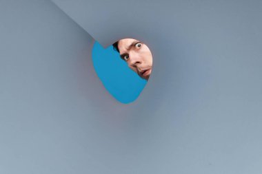 Yuvarlak tüp içine bakan bir adam. Yuvarlak gözlü genç adamı yakından çek.