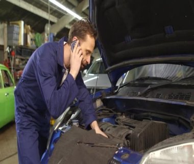 Bir cep telefonu üzerinde bir araba tamir ederken araba sahibiyle konuşurken makinist