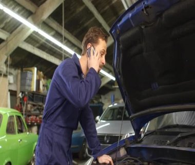 Bir cep telefonu üzerinde bir araba tamir ederken araba sahibiyle konuşurken makinist