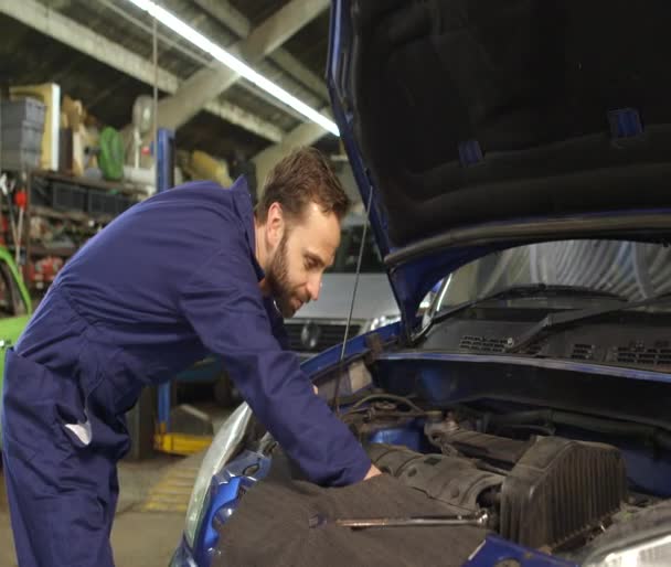 Mekanikern talar på en mobiltelefon med bilägaren medan reparera en bil — Stockvideo