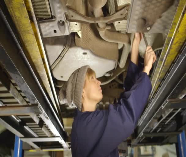 Porträt einer freundlichen Mechanikerin, die unter einem Auto arbeitet — Stockvideo