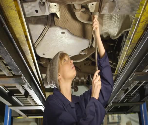 Vrouwelijke mechanic herstellen van een auto in een garage. — Stockvideo