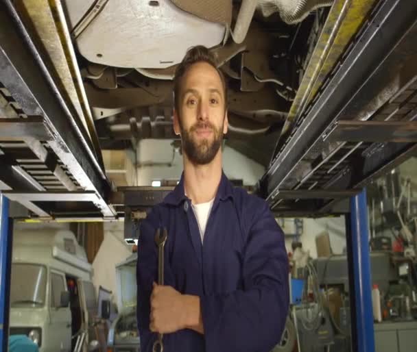 Porträtt av en ung mekaniker arbetar under en bil — Stockvideo