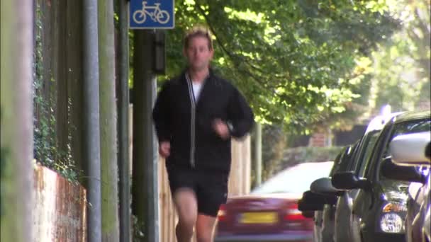 El hombre corre por el pavimento hacia la cámara — Vídeo de stock