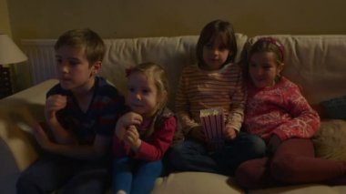 Kanepede oturan ve Tv. Dolly izlerken patlamış mısır yemek çocuk grup