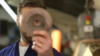 Tamirci bir oto tamirhanesinde motor parçası tamir ediyor.