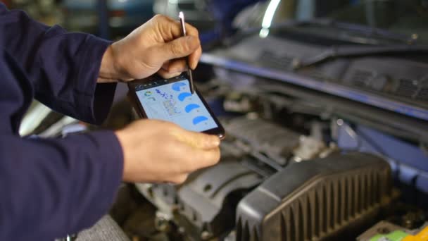 Mechanic entering data into a diagnostic tool while doing routine maintenance — Stock Video