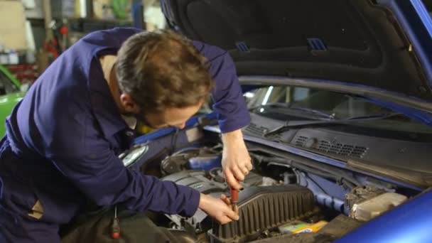 Retrato de un mecánico reparando un motor de coche en un garaje — Vídeos de Stock