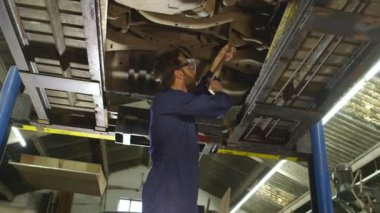 Bir arabanın altında çalışan bir genç makinist portresi