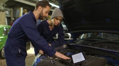Araba tamircisi ve önünde bir araba bir atölye sırasında kadın stajyer
