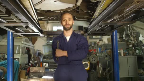 Retrato de un joven mecánico trabajando bajo un coche — Vídeo de stock