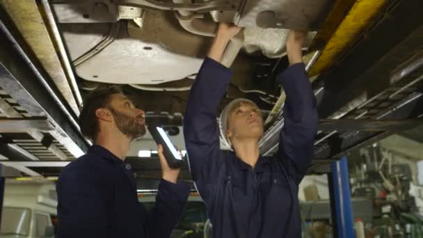 Mechanic toezicht op zijn assistent door onderhoud en service van een auto — Stockvideo