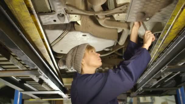 Retrato de una simpática mecánica que trabaja bajo un coche — Vídeo de stock