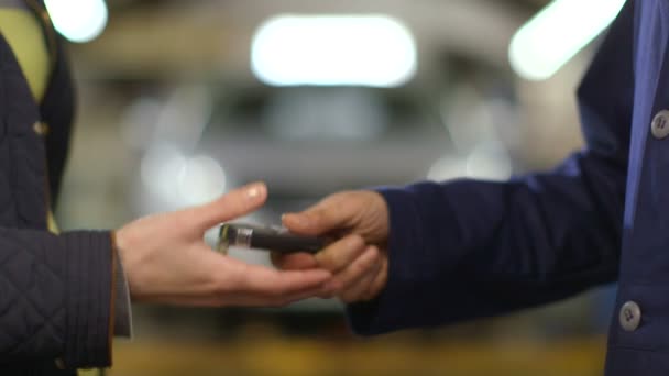 Primer plano de un mecánico entregando una llave de coche a una mujer en un garaje — Vídeos de Stock