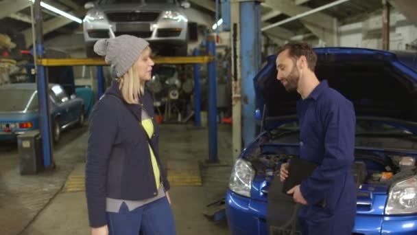 Attraktive junge Frau übergibt Autoschlüssel an Automechaniker — Stockvideo