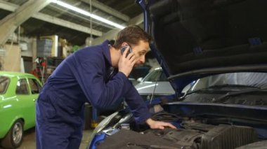 Bir cep telefonu üzerinde bir araba tamir ederken araba sahibiyle konuşurken makinist