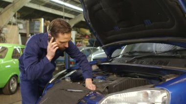 Bir cep telefonu üzerinde bir araba tamir ederken araba sahibiyle konuşurken makinist