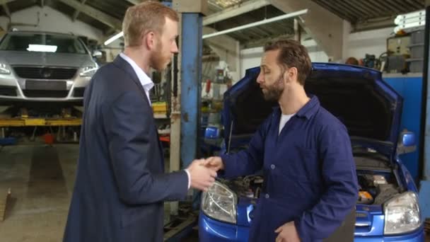 Mladý podnikatel předání klíče od auta k mechanik a dává pokyny fo — Stock video
