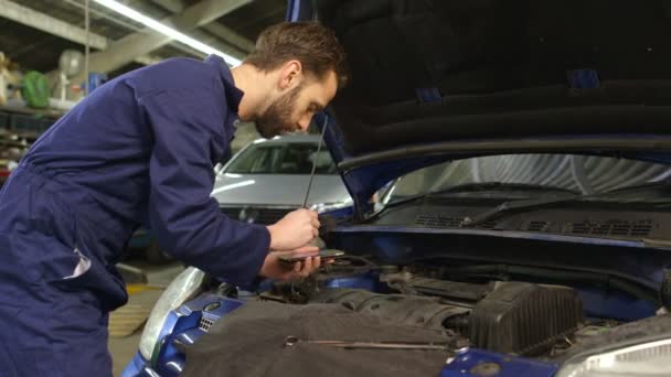 Mechanic entering data into a diagnostic tool while doing routine maintenance — Stock Video