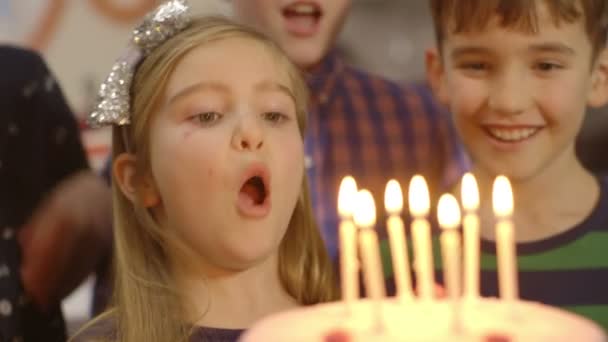 Chica joven trata de soplar todas las velas en su pastel de cumpleaños — Vídeos de Stock
