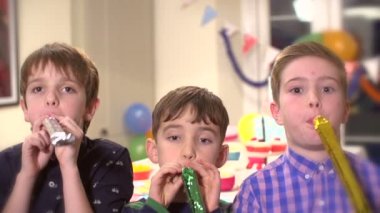 Ağır çekimde parti boynuzları kameraya doğru üfleme üç genç erkek