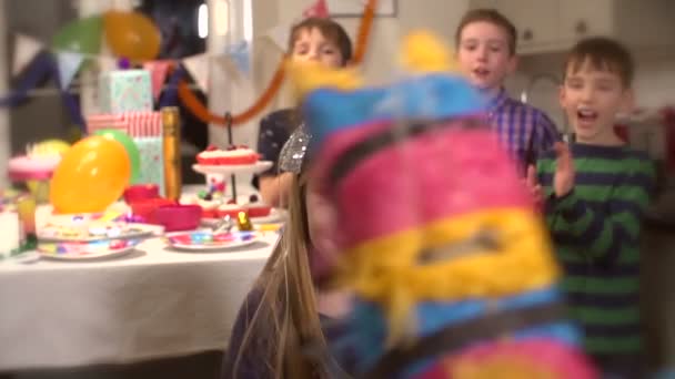 Маленькая девочка бьет пиньяту на вечеринке, пока его друзья подбадривают его медленным движением. — стоковое видео