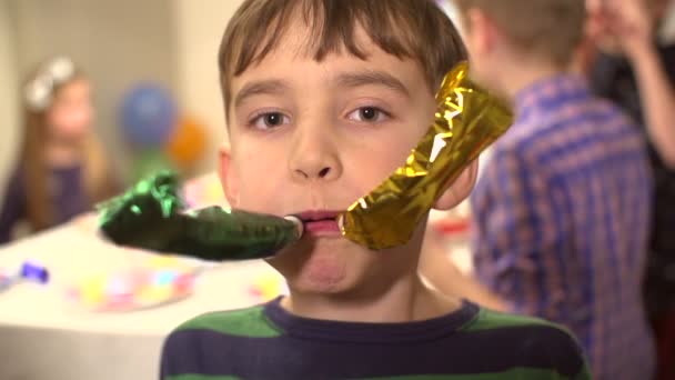 Young boy blowing party horns towards the camera in slow motion — Stock Video