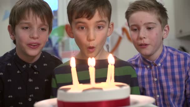 Молодий хлопець намагається підірвати всі свічки на день народження торт у повільному русі — стокове відео
