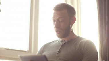 Mutlu çekici genç adam onun tablete görüntülü sohbet sahip