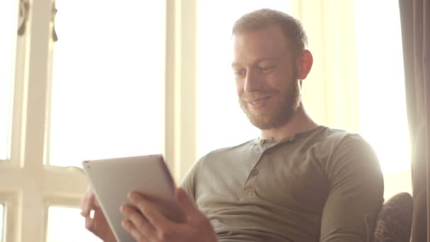 Ευτυχισμένος ελκυστικό νεαρό άνδρα, έχοντας μια συνομιλία μέσω βίντεο σχετικά με το tablet — Αρχείο Βίντεο