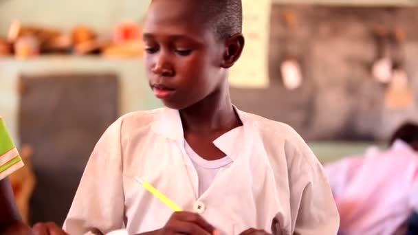 GAMBIA, 08 MARCH 2012: Young African boy works alone in class — Stock Video